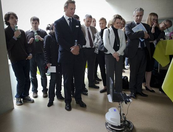 瑞士亿万富翁慈善家尔纳斯特-伯德瑞利(左起第四人)正注视着受马克-安德烈-杜克控制的一个机器人，杜克是瑞士洛桑联邦技术学院的一名部分瘫痪患者