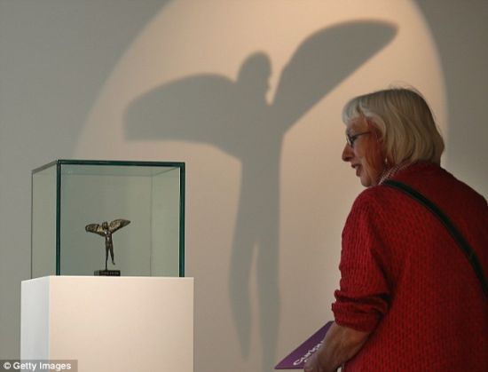 惠康基金会举办的“超人”展现场，一名妇女正在欣赏伊卡洛斯小雕像。此次展览旨在让人们了解人类为了增强身体采取了哪些举措