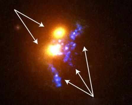 图中左上方为正在相撞的两个巨型椭圆形星系，“珍珠链”位于这两个星系的右下方。