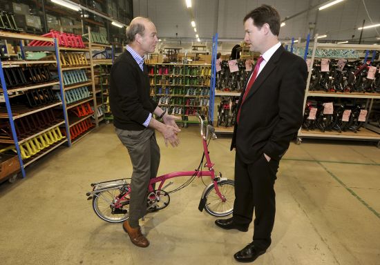 图为克雷格与骑在一辆brompton折叠车上的里