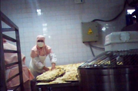 图为和面间的工人在整理次品蛋挞。