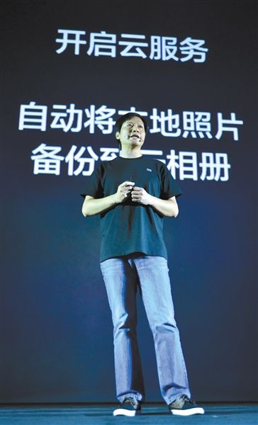 2013年9月5日，在发布会上，小米董事长雷军在讲解自动上传照片的功能。图/CFP