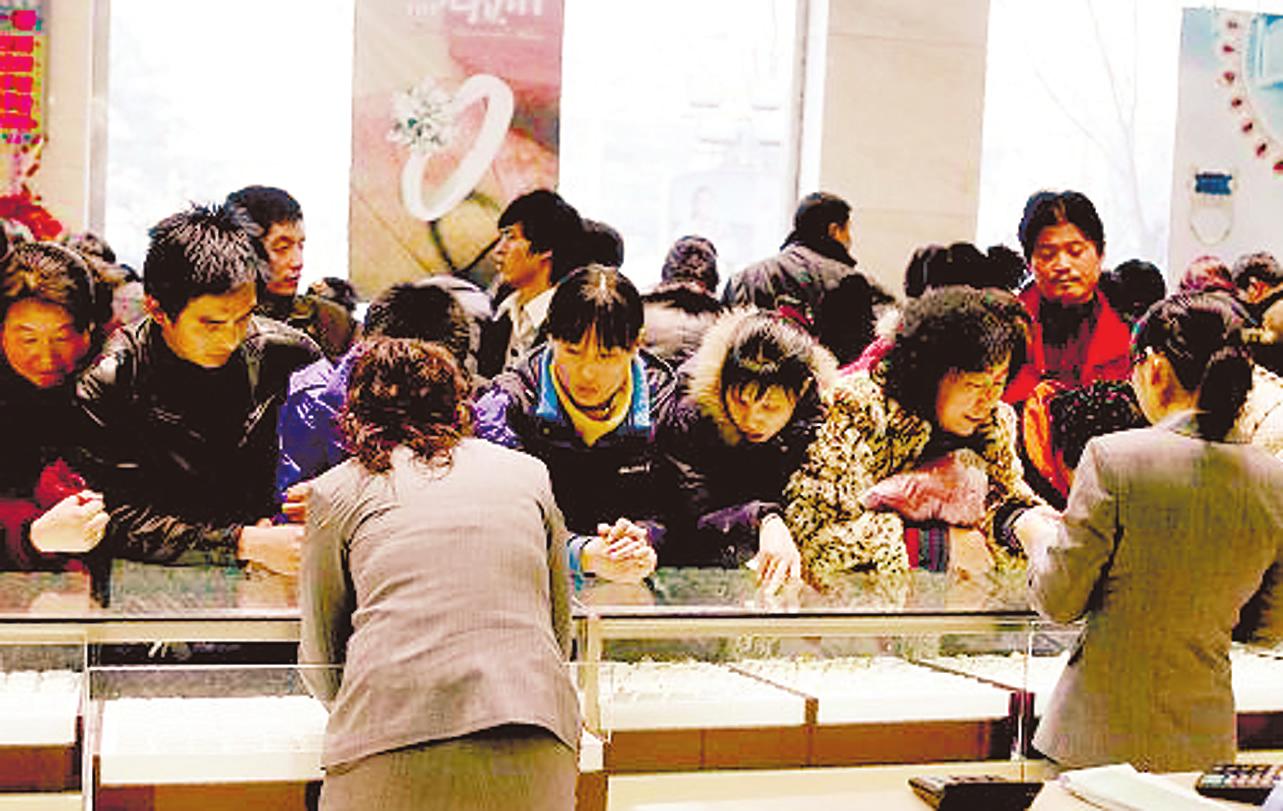 顾客在北京菜百商场柜台前购买黄金饰品