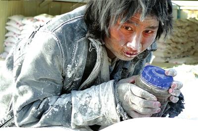 一名工人抱着水杯在成品大白粉堆上发呆。图片来源：天山网 