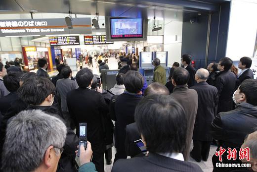 日本近海3月11日发生了强烈地震，首都东京震感强烈。日本气象厅随即发布了海啸警报，称地震将引发约6米高海啸。图为日本东京品川站受强震影响停运，旅客在车站内实时关注最新地震情况。 