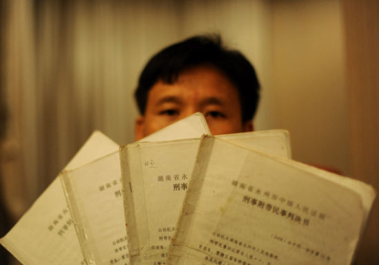 图为8月7日，唐慧的丈夫张辉向记者展示此案先后四次的判决书。新华社记者 白禹 摄