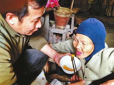 汉达康福协会的吴泽豪喂黄阿婆吃黄桃罐头，黄阿婆十分满足。