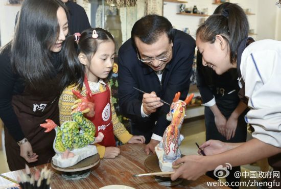 一个小女孩邀总理一同为她的陶器上色。