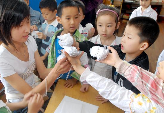 图文:幼儿园小朋友将做好的白纸花交给老师