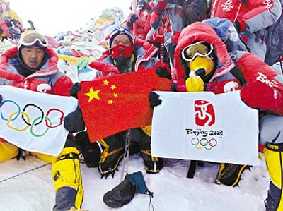 登山队员在峰顶展示中国国旗,奥运五环旗和北京奥运会会徽旗.