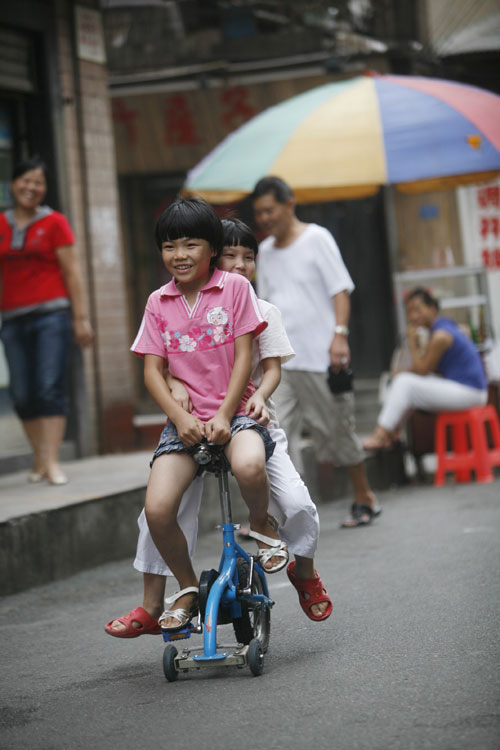 图文:小孩儿骑微型三轮自行车路边玩耍