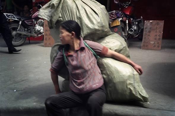 一位背负着沉重包裹的打工妇女.