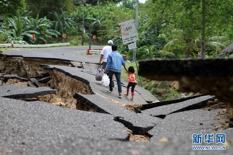 2月7日,在菲律宾东内格罗斯省,当地居民在地震中毁坏的道路上艰难行