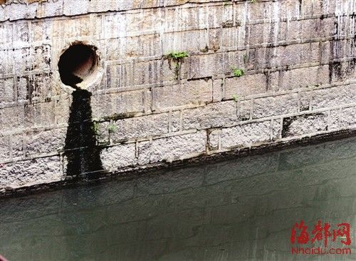 内河一处排污口，正在流出墨黑色污水。