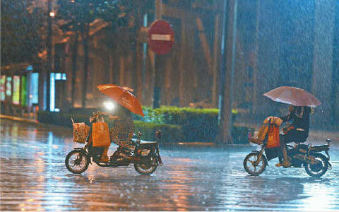 30日晚,济南市民在杆石桥附近冒雨前行.(图片来源:济南时报)