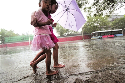 风雨同路情深意笃两名赤脚的小女孩儿共打着一把伞,搂在一起在雨中