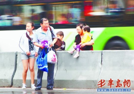 不顾交通安全 一市民拖家带口地翻越护栏(附图)_新闻中心_新浪网