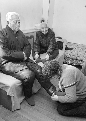 刘凤芝校长双膝脆地为老人穿新袜子■本报记者 贾民 摄