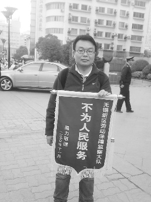 周力在无锡市中心三阳百盛附近举着锦旗。图片来源：现代快报