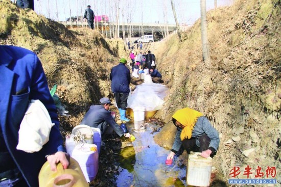 附近村民拿着桶和壶来舀花生油。