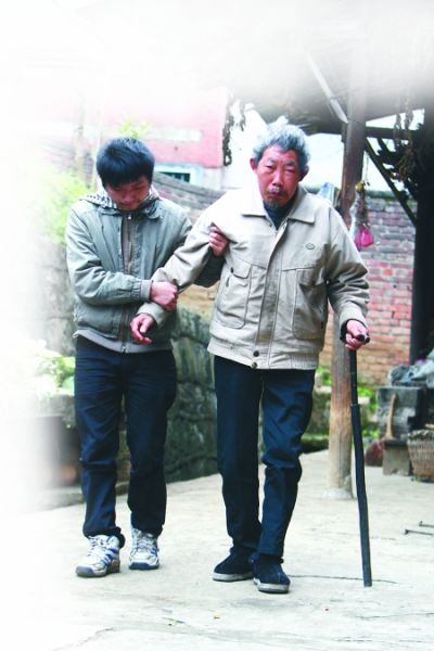 昨日，綦江縣打通鎮，吳清亮攙扶著養父吳天明在院子里散步。記者 龍在全 攝