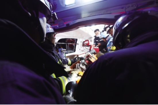 消防人员将女子遗体抬进救护车。