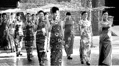 少林寺山门前，10余名女子手撑素油伞，身穿颜色艳丽的旗袍，迈着猫步在庙宇前走秀。