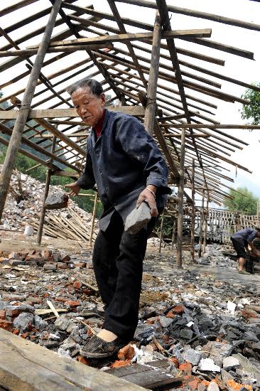 图文:映秀镇渔子溪村村民在木屋旁清理砖头