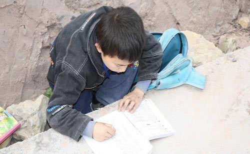乡村小学生趴在马路沿上写作业(组图)