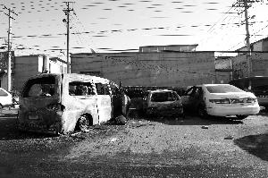 受殃及的两辆车停在被烧毁的面包车旁。昨日，一男子在面包车中过夜，被烧身亡。本报记者 韩萌 摄 