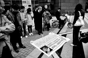 昨日，在江苏大厦旁边，下跪女子的宣传单引来不少围观市民。