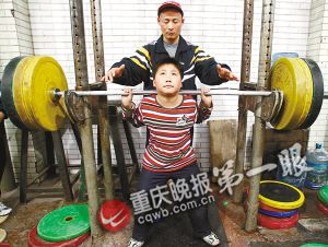9岁的徐玮在教练保护下挑战120公斤的杠铃。