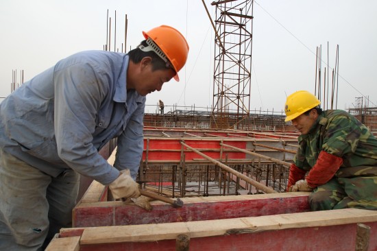 3月23日,郑黄生(右)和范建冲在江苏启东一建设工地工作.