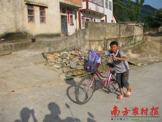 骑车上学的学生艰难地推车上坡