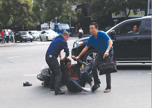 骑摩托车的歹徒被擒住。右蓝色T恤男青年为温州商报记者金俊，左边蓝衣男子为热心市民。温州商报