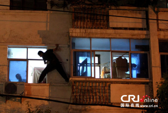 2013年09月02日，河南省郑州市一小区内闻到尸臭味，女子拒不开门挥舞菜刀，郑州特警从窗外强制制服该女子。图片来源：小东/CFP