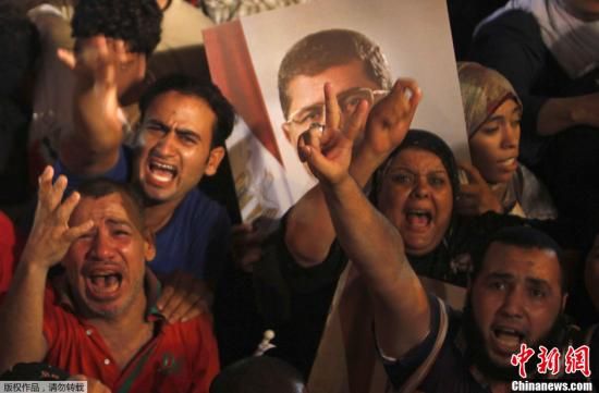 资料图：7月4日，埃及军方发表声明表示，总统穆尔西已经下台。图为埃及开罗，穆尔西支持者在一处清真寺广场高举穆尔西肖像以示抗议。