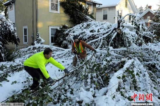 美国东部地区29日开始遭遇的多年罕见的早到的大雪。30日，暴雪已经造成五个州的超过400万户居民家中断电。此外还有5人死亡。图为10月30日，在纽约州的哈德逊街，几名工人在清理街道上的积雪。