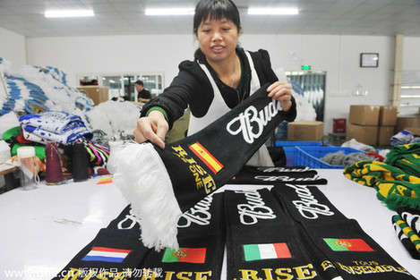 A female worker examines fan scarves of Spain, the Netherlands, Italy and Portugal produced for the 2014 Brazil World Cup at a manufacturing factory in Lin'An city, East China's Zhejiang province, April 26, 2014. [Photo / IC]