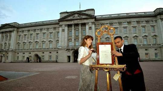 The press Secretary to Britain's Queen Elizabeth, Ailsa Anderson, and footman Badar Azim, place a notice formally announcing the birth of a son to Prince William and Catherine, Duchess of Cambridge, in the forecourt of Buckingham Palace, in central London July 22, 2013.[Photo/Agencies] 