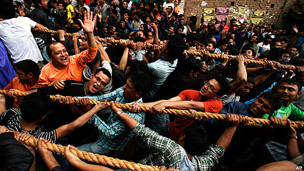 A crowd of Nepalese men pulling on ropes