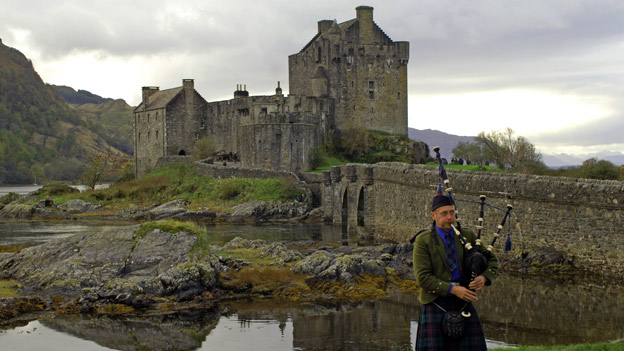 A piper plays his bagpipes outside Eilean Donan Castle in Scotland
