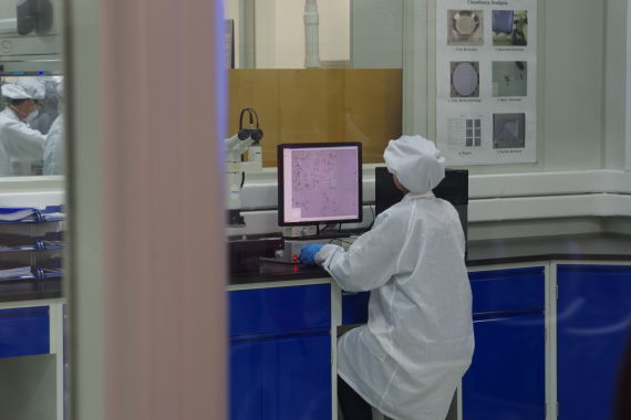 检测工人在无尘车间内利用电子显微镜对工件进行检测
