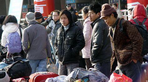 图为郑州火车站广场前几位等待进站候车的返乡农民工。中新社发 李志全 摄