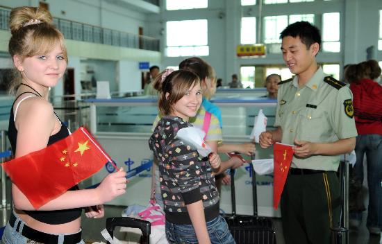 6月30日,吉林省珲春边防检查站边检人员(右)向入境旅客赠送中国国旗和