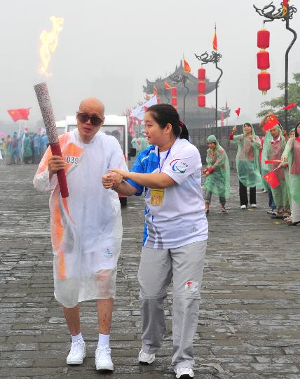 会圣 正文 8月29日,火炬手董应龙(左)在工作人员的搀扶下传递火炬