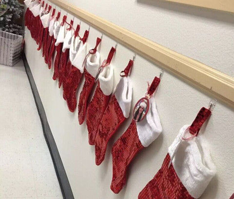 在幼儿园前厅挂着老师圣诞礼物袜子,袜子上照片后面还标着老师想要的