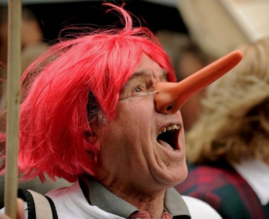 图为一名抗议者头戴红发,扮成长鼻子匹诺曹