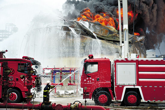8日,救援人员用水枪给火场附近的消防车降温.