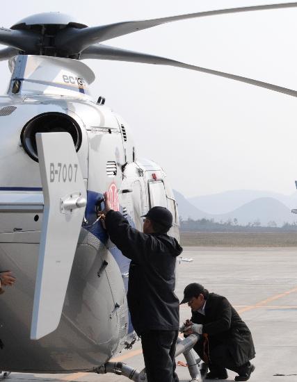 图文:两位飞机机械师在出发前检查巡线直升机